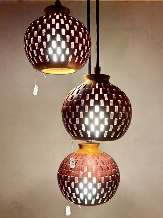 Three-globe handmade bloodwood and canarywood pendant chandelier on display with staggered heights showcasing each sphere