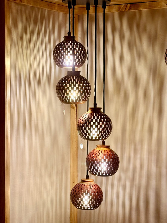 Five-globe handmade bloodwood and canarywood pendant chandelier casting dramatic lattice shadow patterns on the wall