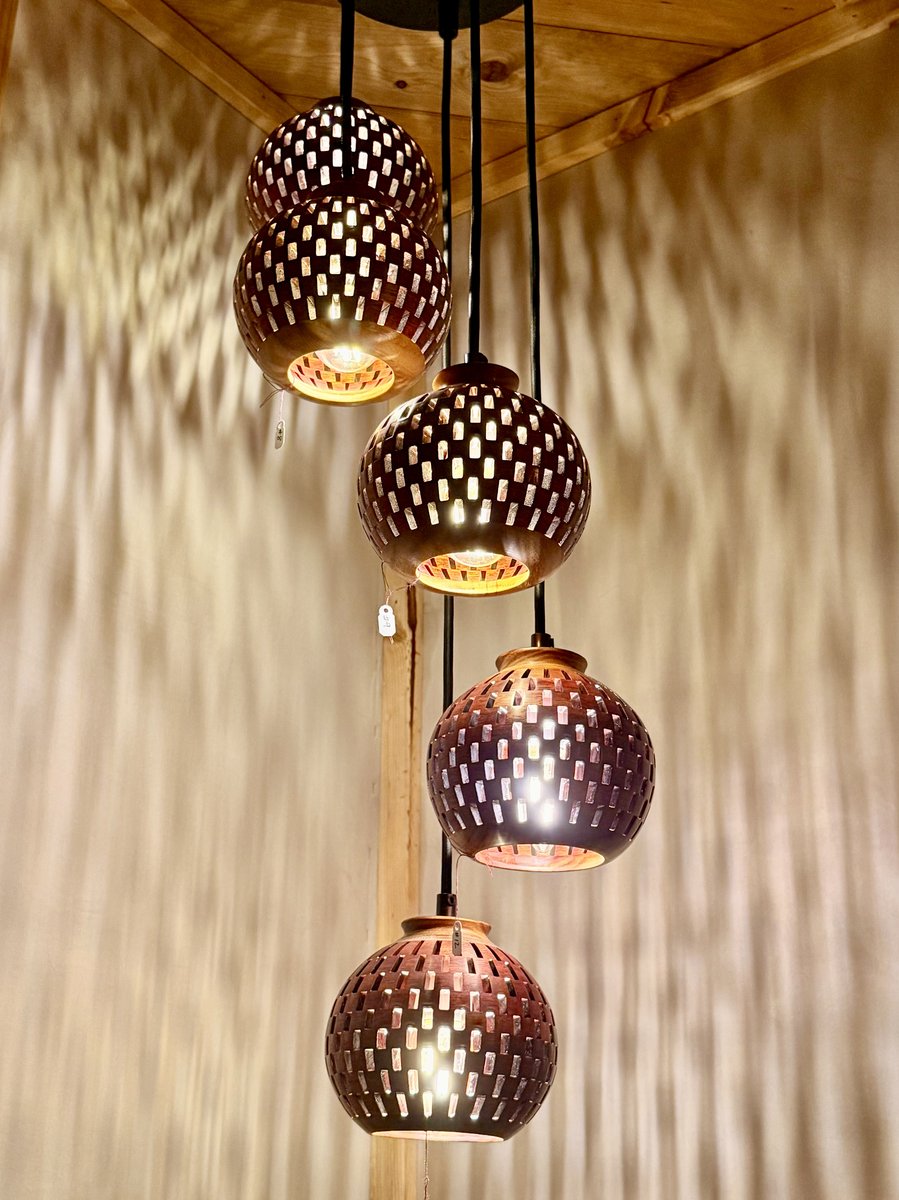 Five-globe handmade bloodwood and canarywood pendant chandelier glowing warmly, highlighting rich wood grain and light play