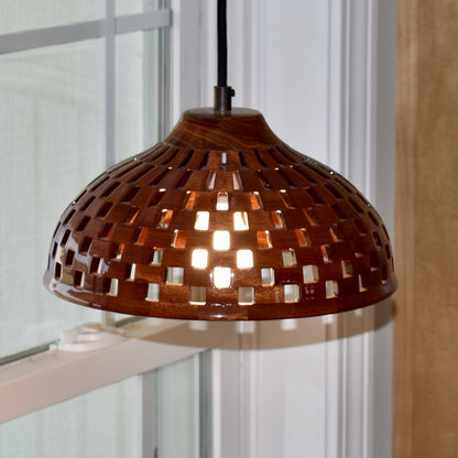 Handmade bloodwood dome pendant light hanging near a window, natural light highlighting the rich red-brown wood grain
