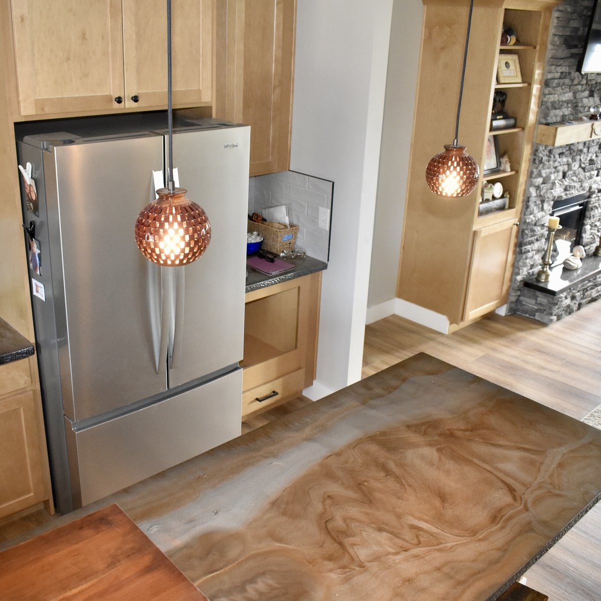 Overhead angle of handmade bloodwood globe pendant lights installed in a kitchen with dark granite countertops