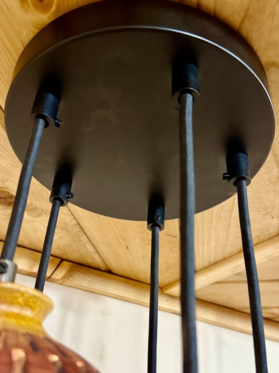 Close-up detail of black metal multi-pendant canopy ceiling plate with woven cord attachment points for a handmade wood chandelier