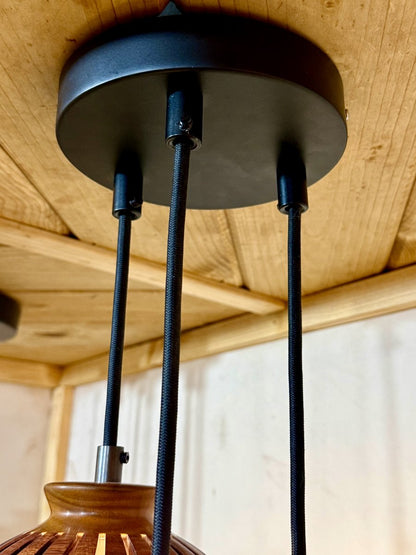 Wide view of a black metal multi-pendant canopy ceiling plate showing cord arrangement for a handmade wood globe chandelier